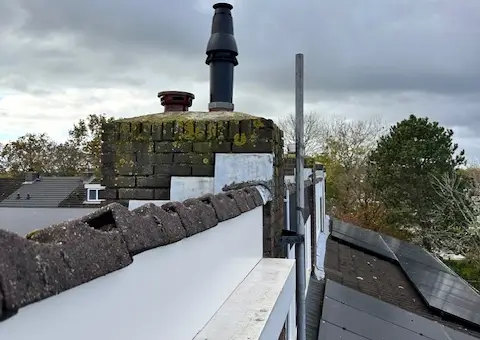 Veilige, nieuwe zwarte rookgasafvoer en dakdoorvoer geïnstalleerd op een dak naast zonnepanelen in Castricum.