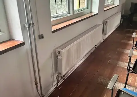 Zichtbaar en strak gemonteerd leidingwerk met lange paneelradiatoren voor optimale verwarming van een pand in Schagen.